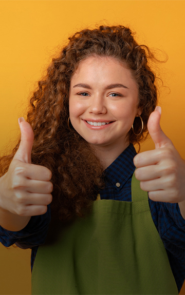 Ein Mädchen lächelt fröhlich und hält beide Daumen hoch.