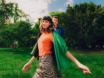 Eine Frau auf einer Wiese, im Hintergrund sieht man Bäume.