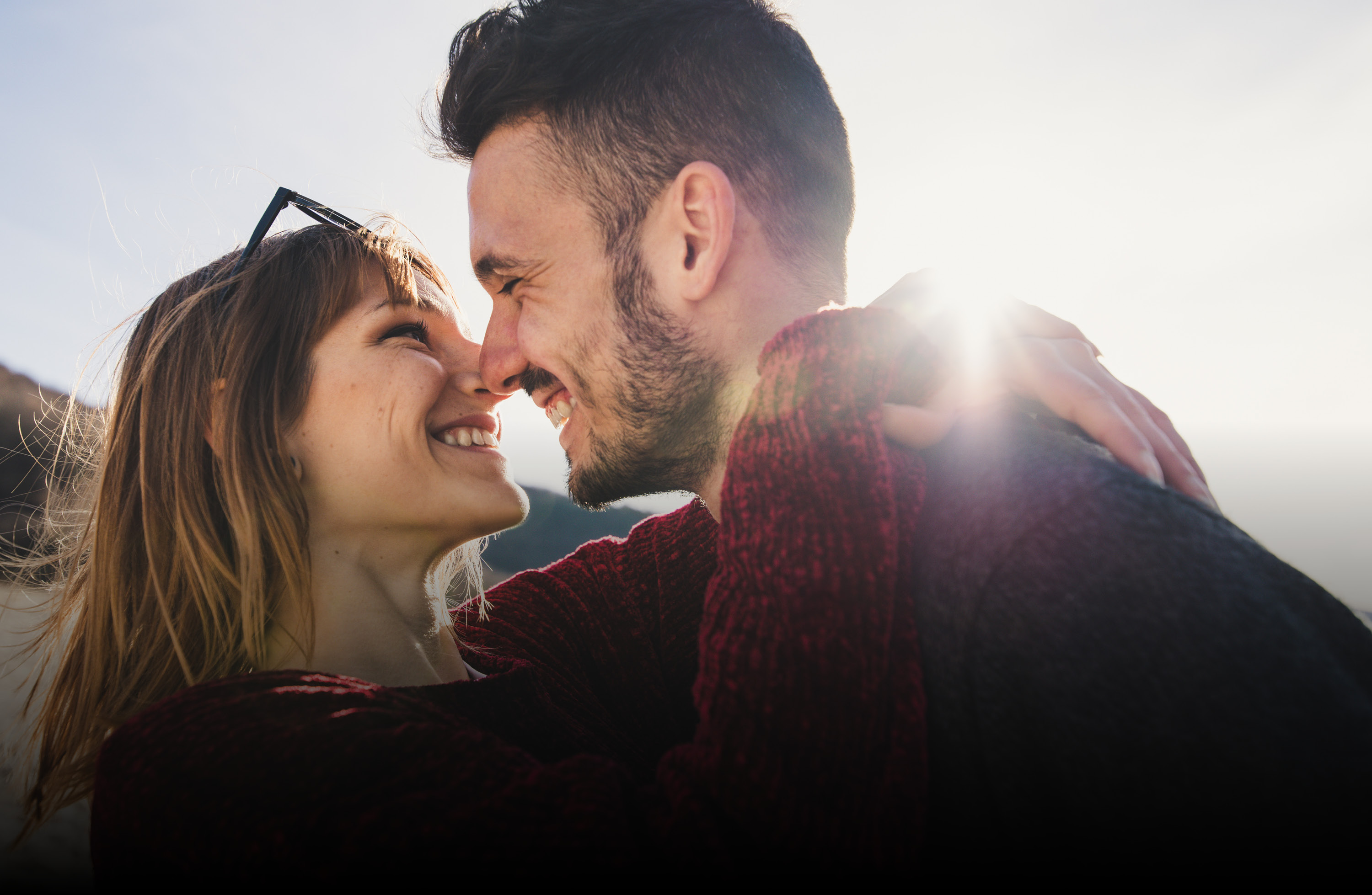 Zwei Personen genießen einen gemeinsamen Moment im Freien. Das warme Sonnenlicht und die Nähe der Personen vermitteln Geborgenheit sowie den Blick in eine gemeinsame Zukunft.