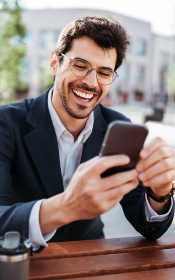 Ein Mann hält sein Smartphone in der Hand und lacht zufrieden